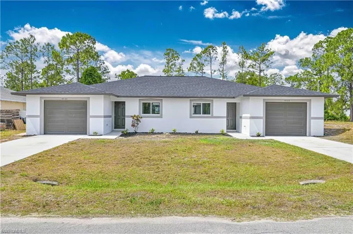 Single story home with a garage, a front yard, stucco siding, driveway, and roof with shingles