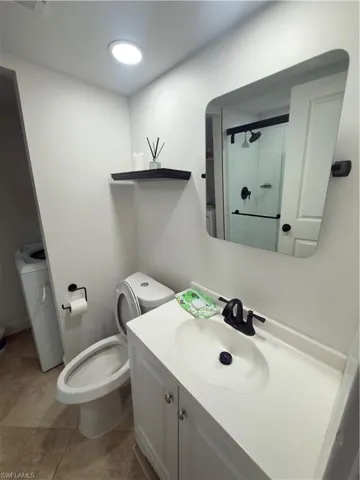 Full bathroom with vanity, a shower stall, washer / clothes dryer, and light tile patterned floors