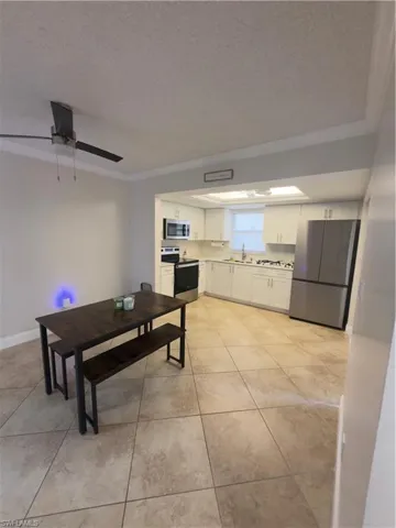 Dining space with a textured ceiling, a ceiling fan, and light tile patterned floors
