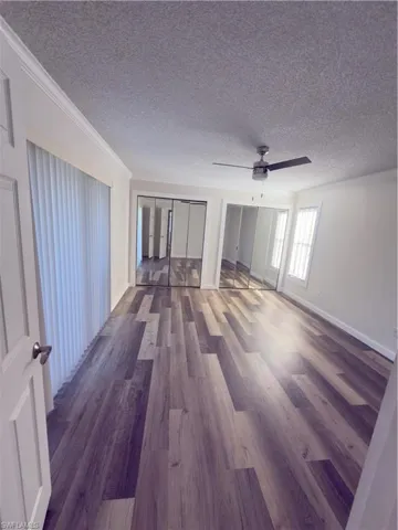 Spare room with wood finished floors, crown molding, a textured ceiling, and a ceiling fan