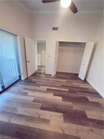 Unfurnished bedroom with dark wood-style floors, ornamental molding, a closet, and a ceiling fan