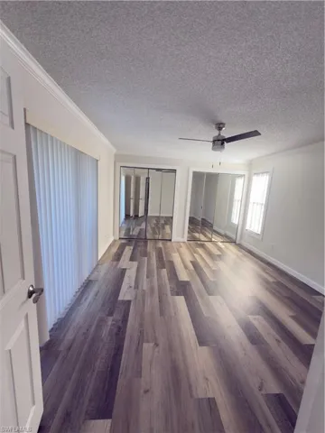 Empty room featuring ornamental molding, wood finished floors, a textured ceiling, and ceiling fan