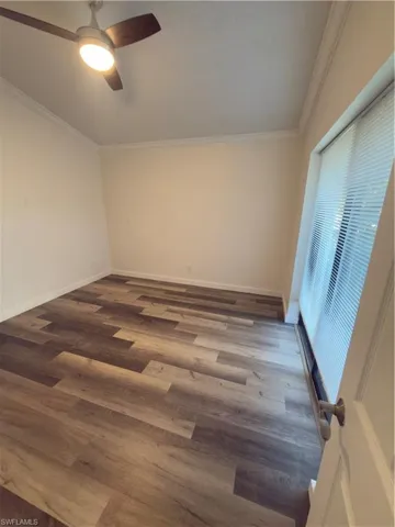 Spare room featuring crown molding, wood finished floors, and a ceiling fan