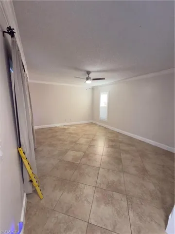 Unfurnished room featuring crown molding, light tile patterned floors, a textured ceiling, and ceiling fan