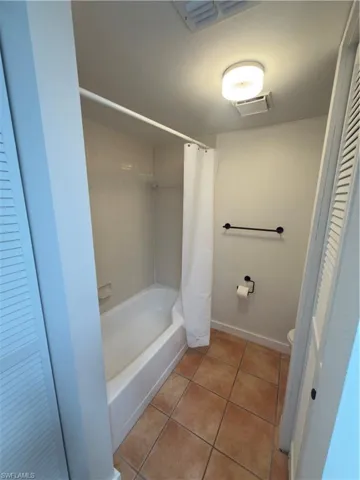 Full bath with light tile patterned flooring, shower / bath combo, and a closet