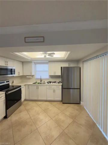 Kitchen featuring range, white cabinetry, fridge, ceiling fan, and light countertops