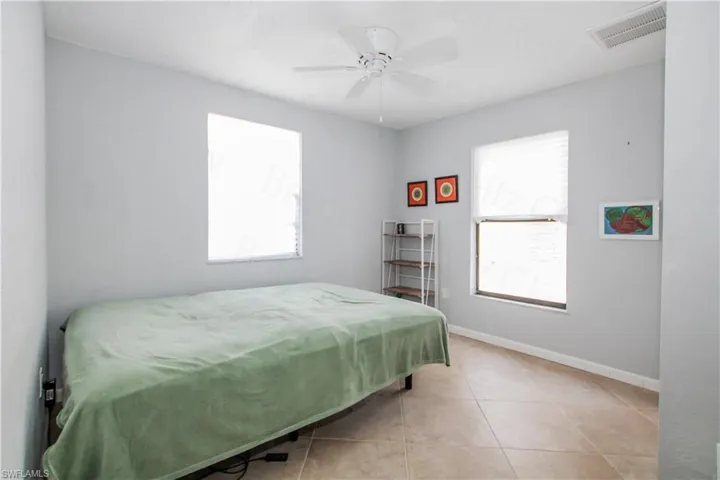 Tiled bedroom featuring ceiling fan