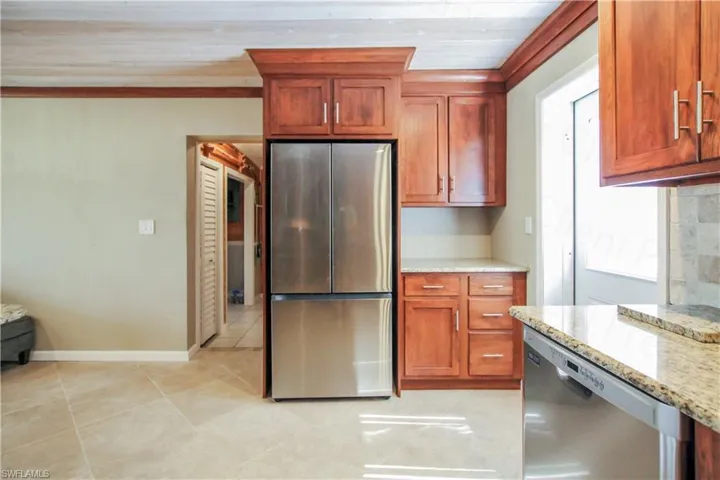 Kitchen featuring ornamental molding, appliances with stainless steel finishes, light stone counters, wood ceiling, and light tile floors