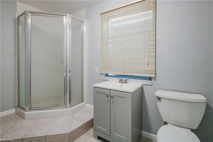 Bathroom with tile flooring, walk in shower, vanity, and toilet