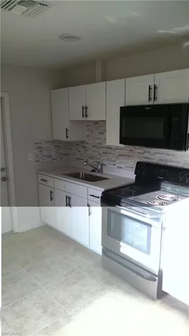 Kitchen featuring electric range, white cabinetry, black microwave, and backsplash