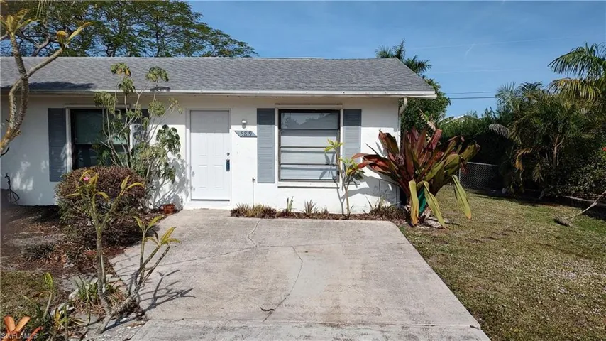 View of front facade featuring roof with shingles and stucco siding