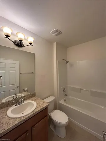 Bathroom featuring bathing tub / shower combination, vanity, and light tile patterned flooring
