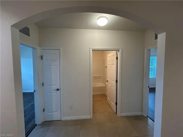 Corridor featuring arched walkways and light tile patterned floors