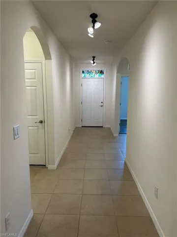 Hallway featuring light tile patterned floors and arched walkways