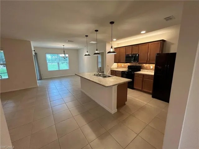 Kitchen featuring black appliances, backsplash, light tile patterned floors, a kitchen island with sink, and recessed lighting