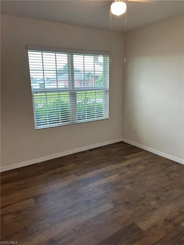 Empty room with baseboards and dark wood-style floors