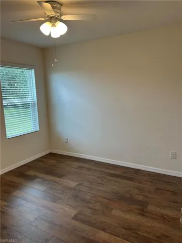 Spare room with dark wood finished floors and a ceiling fan
