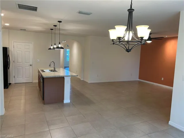 Kitchen with a center island with sink, arched walkways, recessed lighting, a chandelier, and pendant lighting