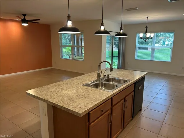 Kitchen with brown cabinets, open floor plan, healthy amount of natural light, and light tile patterned floors
