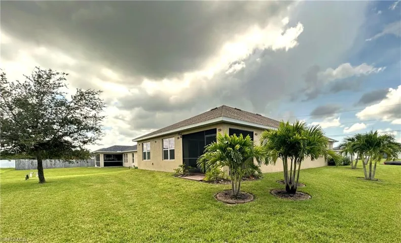 Rear view of property featuring a sunroom, a lawn, and stucco siding