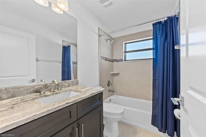 This guest bathroom is light and bright, with a granite countertop and a combination tub and shower.