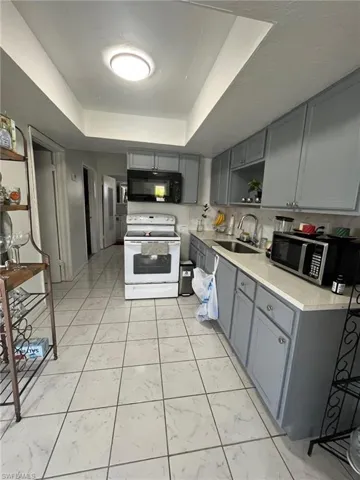 Kitchen featuring white appliances, backsplash, a raised ceiling, sink, and gray cabinets