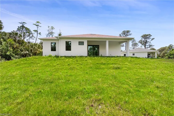 Back of property with a yard and stucco siding