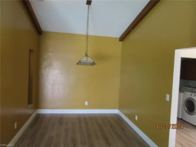 Unfurnished dining area with washer / dryer, hardwood / wood-style flooring, and lofted ceiling