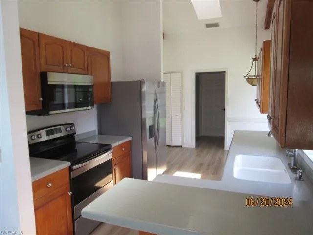 Kitchen featuring light hardwood / wood-style floors, appliances with stainless steel finishes, hanging light fixtures, and sink