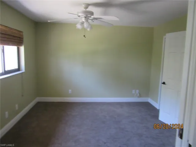 Unfurnished room with dark colored carpet and ceiling fan
