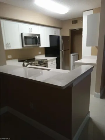 Kitchen featuring white cabinets, washer / dryer, stainless steel appliances, and kitchen peninsula