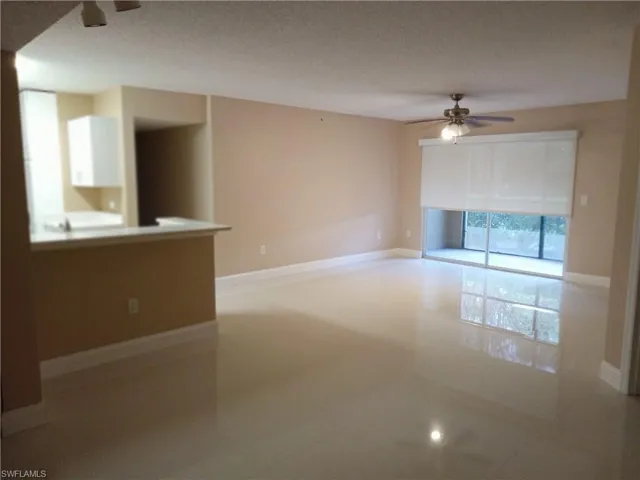Unfurnished living room with tile patterned floors, ceiling fan, and a textured ceiling