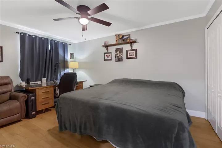 Guest bedroom featuring a closet, light hardwood/wood-style floors, crown molding, and ceiling fan