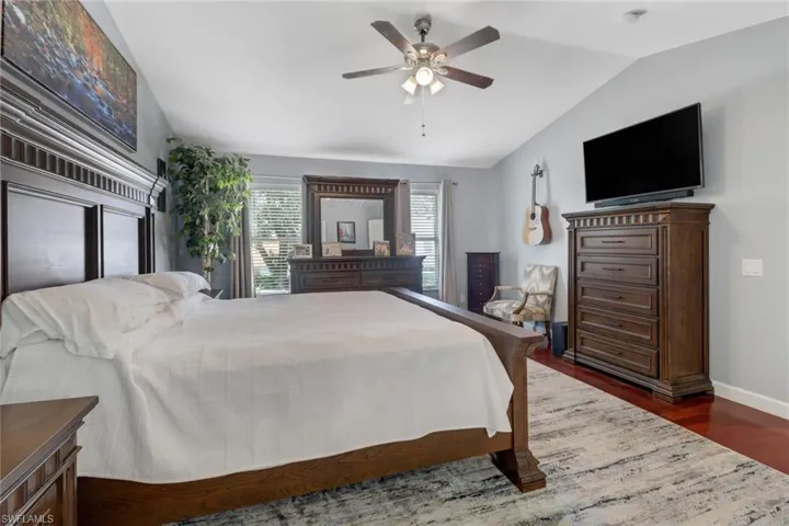 Primary bedroom featuring ceiling fan, lofted ceiling, and dark hardwood/wood-style floors
