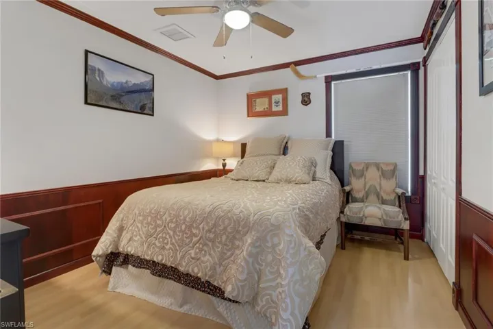 Bedroom featuring ornamental molding, light wood-type flooring, a closet, and ceiling fan
