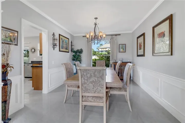 Enjoy your meals in the dining room featuring a notable chandelier, ornamental molding, and light tile patterned floors
