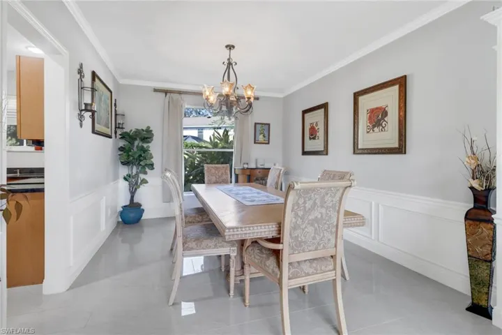 Tiled dining room featuring ornamental molding and a notable chandelier