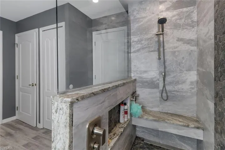 Bathroom featuring a tile shower and hardwood/wood-style floors.  The shower also has an attached bench.