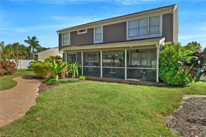 Back of property featuring a sunroom and beautifully landscaped lawn