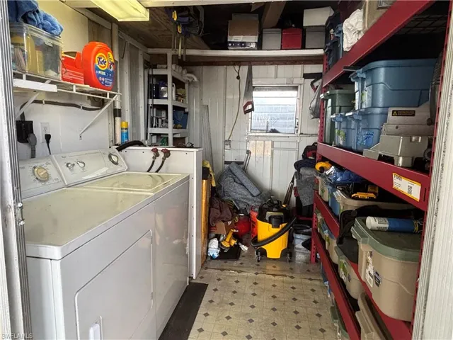 Utility space featuring a washer and dryer, shelving for storage, and a window