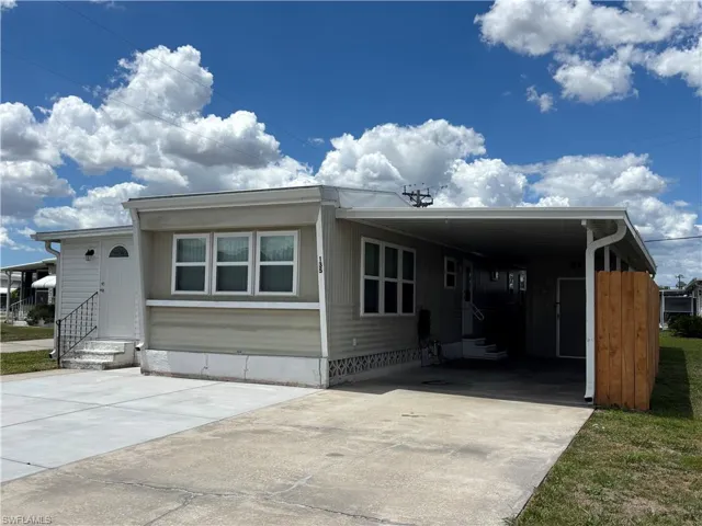 The property features a light-colored exterior, a white front door with a decorative window, and multiple windows with white frames