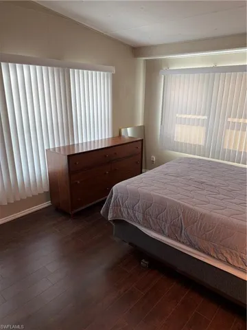 Bedroom featuring dark hardwood style flooring and vertical blinds on the windows