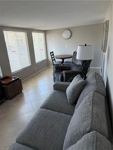 The living area features two windows with blinds, light-colored tile flooring, and light-toned walls