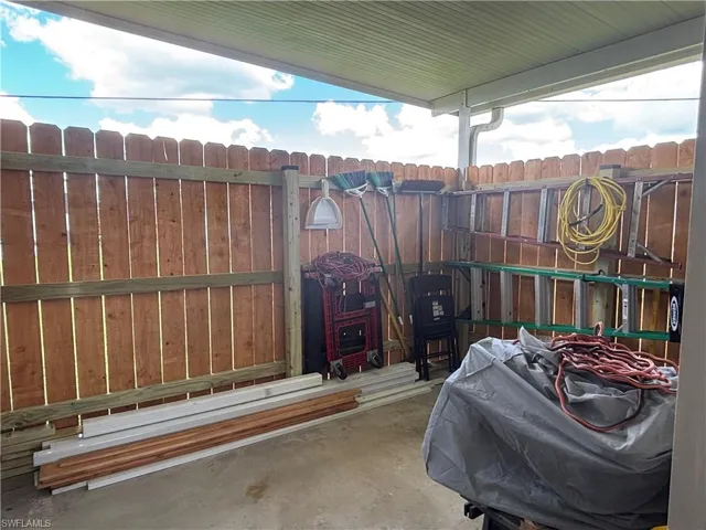 The property features a covered patio area with a concrete floor and a wood fence