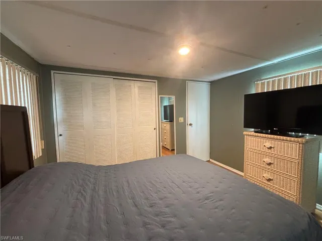 The room features a textured ceiling, a white paneled closet, and window blinds