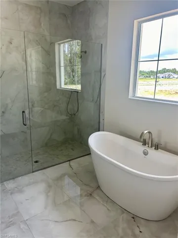 Bathroom featuring independent shower and bath, a wealth of natural light, and tile patterned flooring