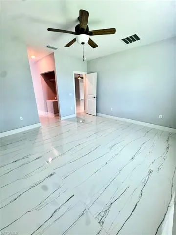Unfurnished room featuring ceiling fan and marble look tiles