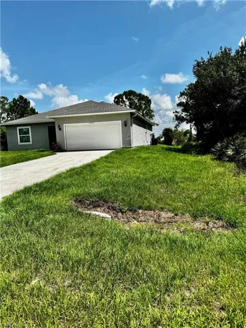 View of home's exterior with stucco siding, an attached garage, driveway, and a lawn