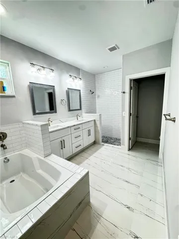 Bathroom with a stall shower, a bath, double vanity, and marble finish flooring