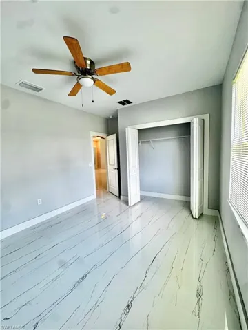 Unfurnished bedroom featuring light marble finish floors, a closet, and ceiling fan